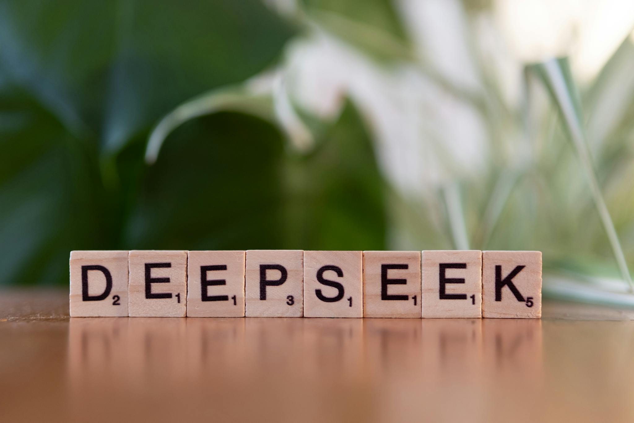 Wooden letter tiles spelling 'DEEPSEEK' on a table with a blurred green background.